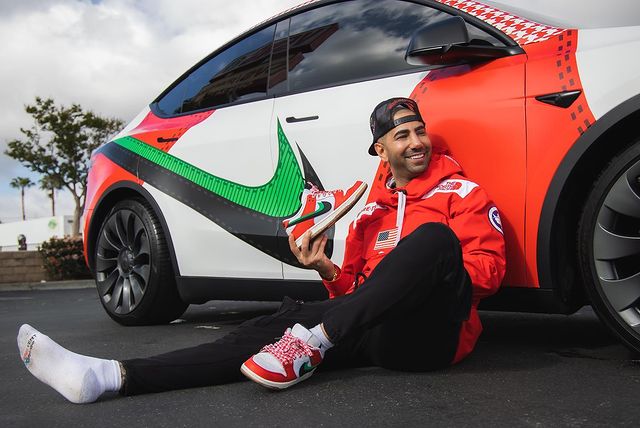 Yousef Saleh Erakat in an orange hoodie and black pants sitting in front of his luxurious car.